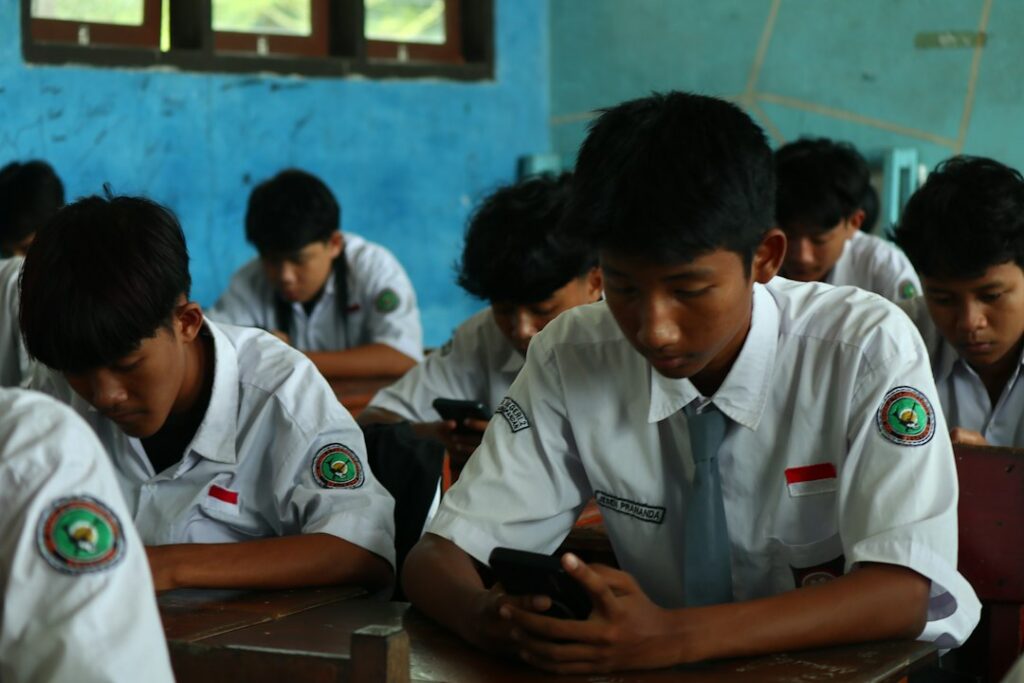School students in uniform checking matric result on phones