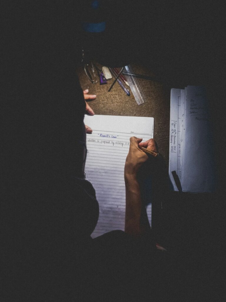 Student writing answers on exam paper